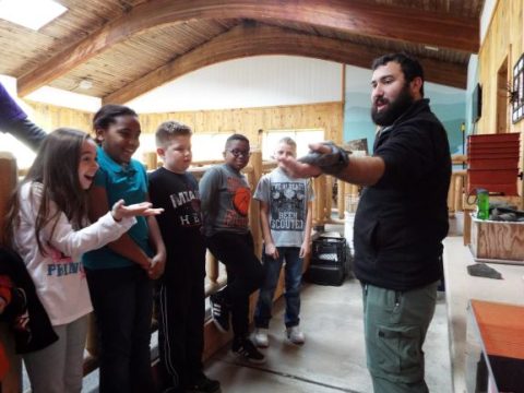 A PEEC instructor is showing students a black rat snake in PEEC's EcoZone Discovery Room