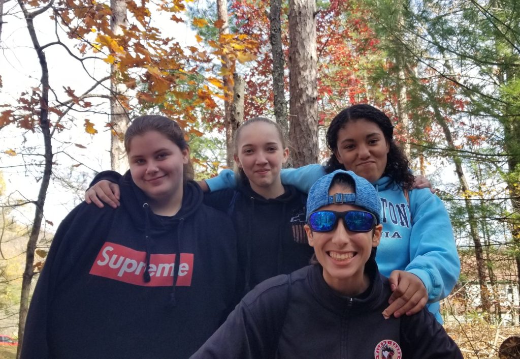 A group of 4 teen girls smiling in the woods