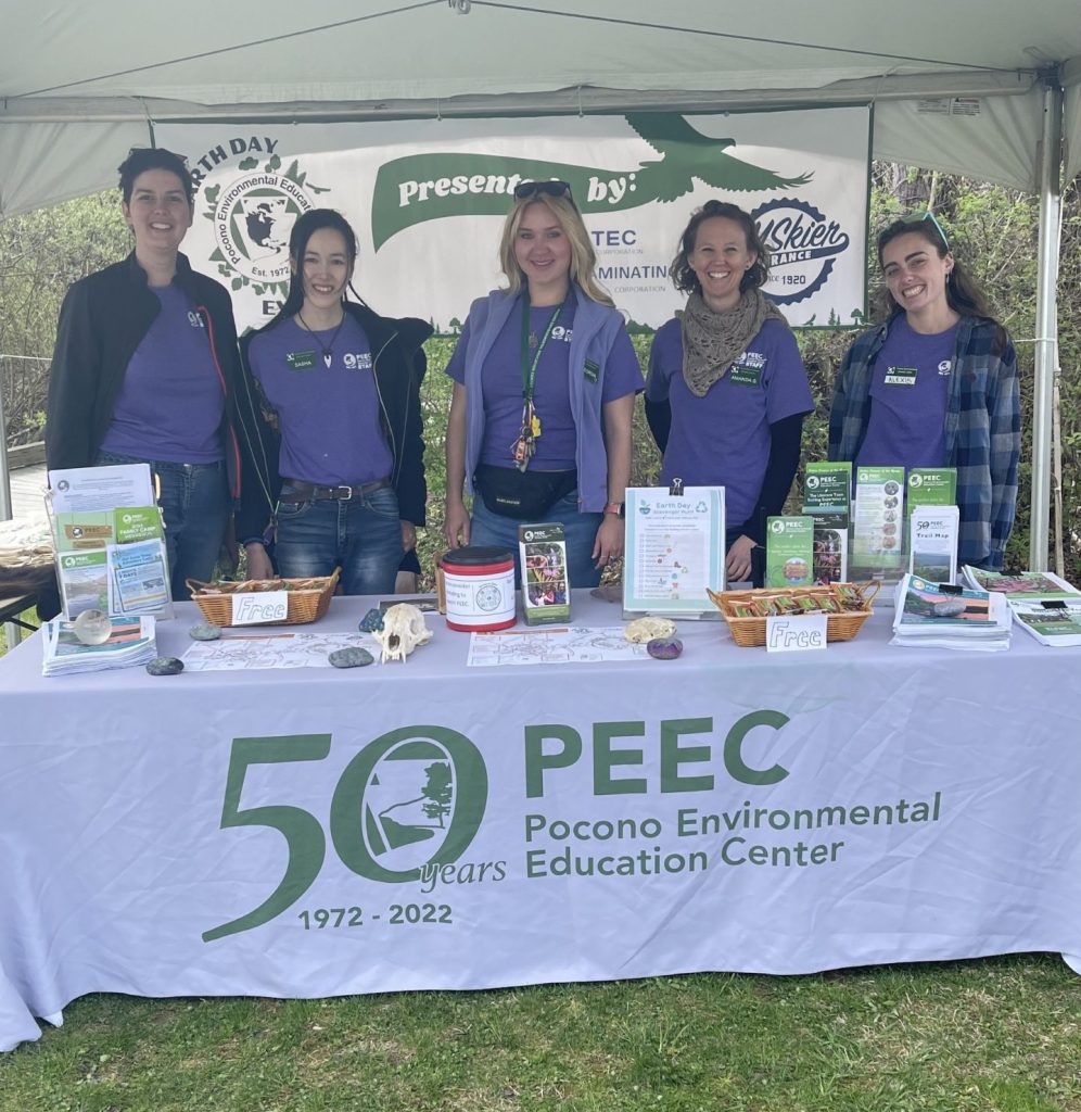 Five PEEC staff members in matching shirts standing at the Welcome Tent
