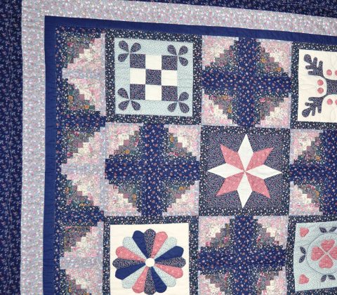 A quilt with various shades of indigo and pink.