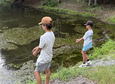 Two teens fishing at a pond