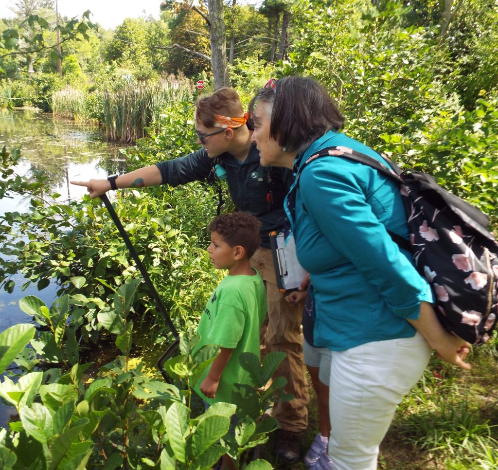 A PEEC instruction pointing out something in the pond to a young boy and a woman